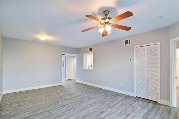 an empty room with wooden floor fan and windows