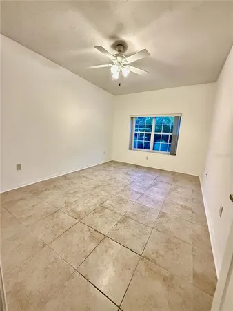 an empty room with windows and ceiling fan