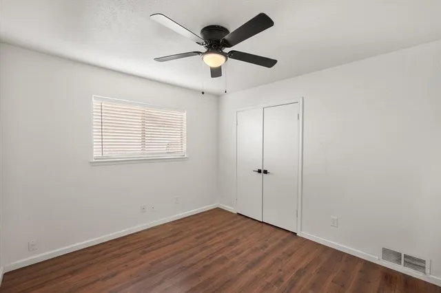 an empty room with wooden floor ceiling fan and windows