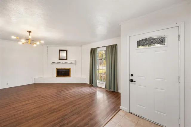 a view of an empty room with wooden floor and a fireplace