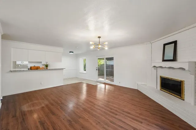 an empty room with wooden floor fireplace and windows