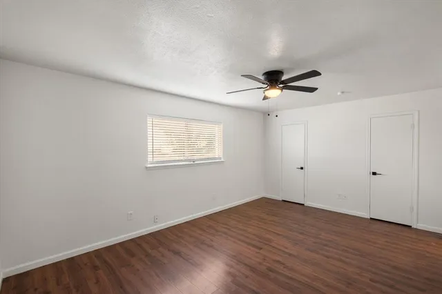 an empty room with wooden floor and ceiling fan