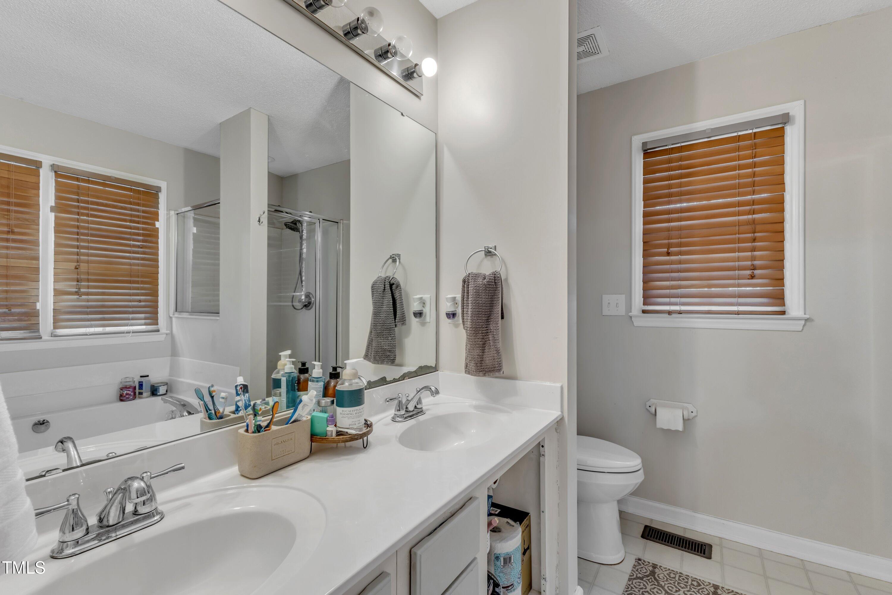 9512 Anson Grove Lane Raleigh, NC 27615 - Photo 22 of 39 a bathroom with double vanity sinks a toilet and a mirror