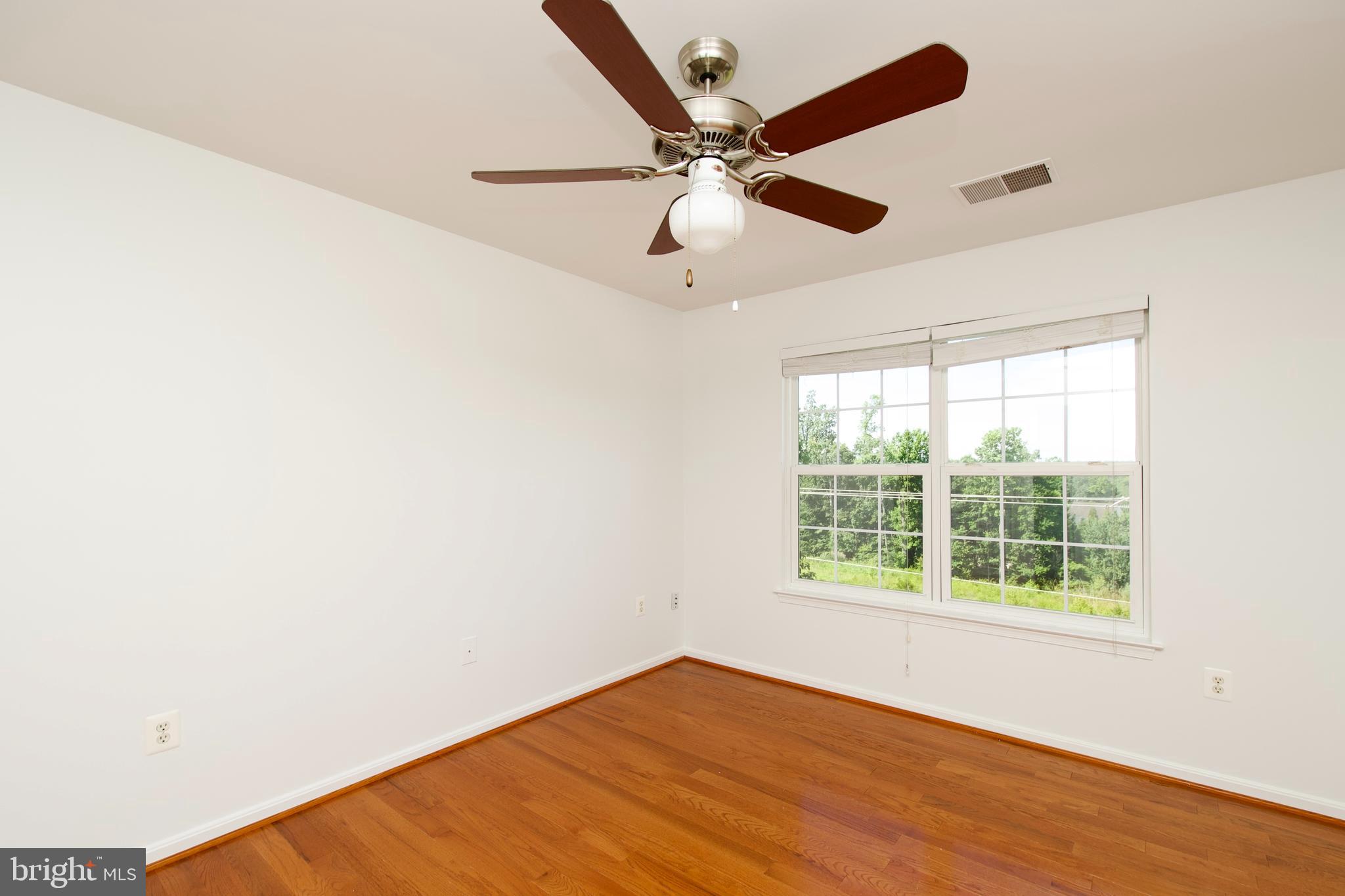 17528 October Glory Loop Dumfries, VA 22026 - Photo 28 of 50 an empty room with wooden floor fan and windows