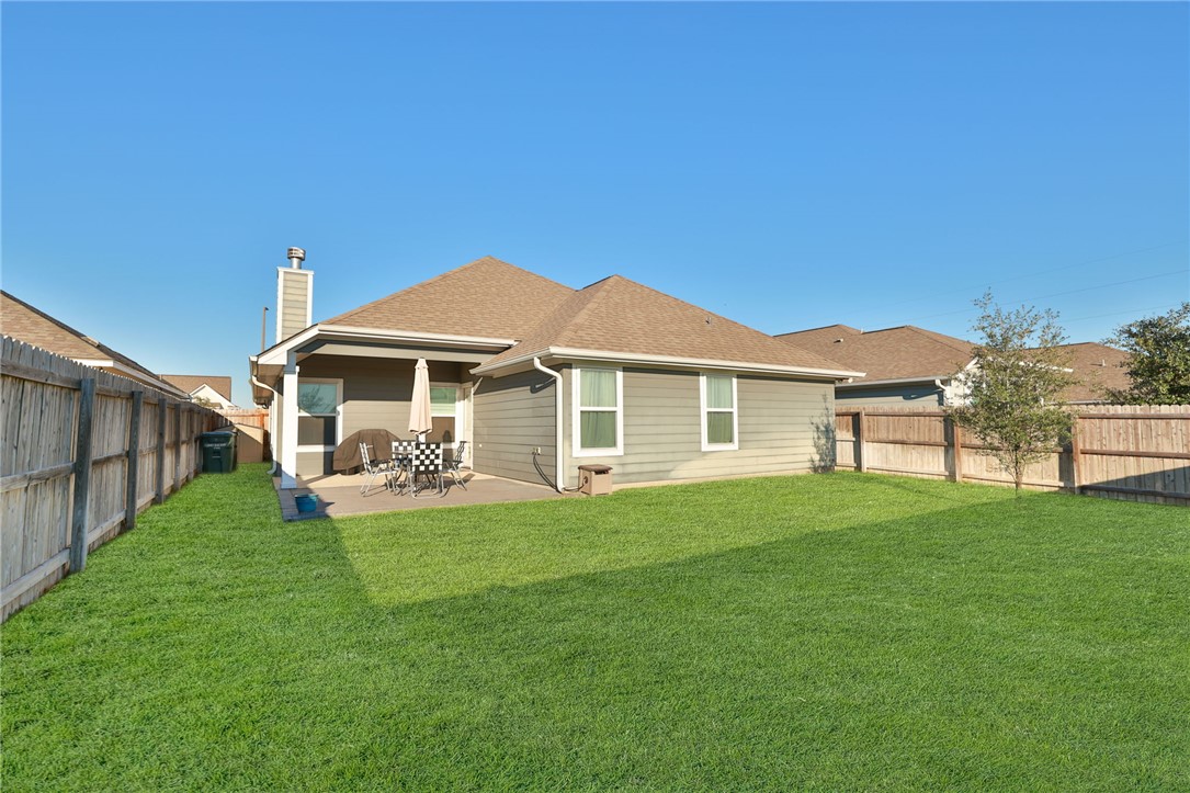 3417 Calmar Court Bryan, TX 77808 - Photo 29 of 31 Back of property featuring a shingled roof, a fenced backyard, a chimney, and a patio