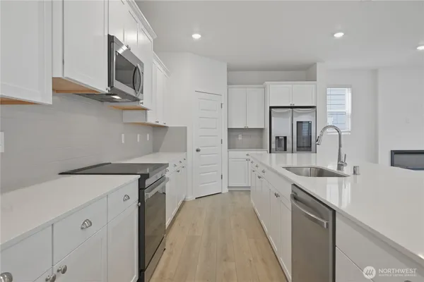 a large kitchen with stainless steel appliances granite countertop a stove a sink and white cabinets