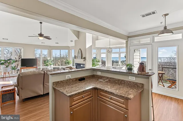 a kitchen with stainless steel appliances granite countertop a stove top oven a sink dishwasher a dining table and chairs with wooden floor