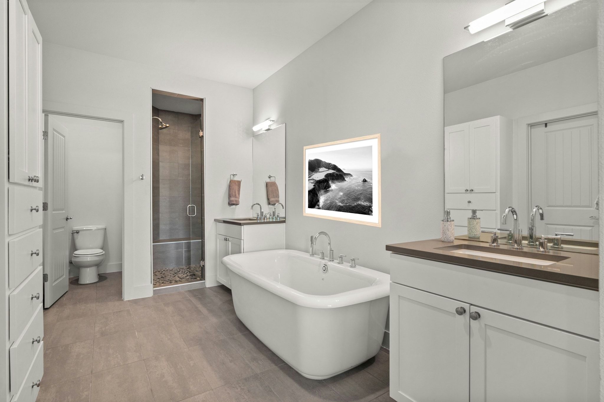 8110 Ranch Road 2222, Unit 92 Austin, TX 78730 - Photo 17 of 40 Spacious bathroom featuring a freestanding soaking tub, a walk-in shower with pebble tile floor, dual vanity sinks with extensive cabinetry, and light-toned floor tiling