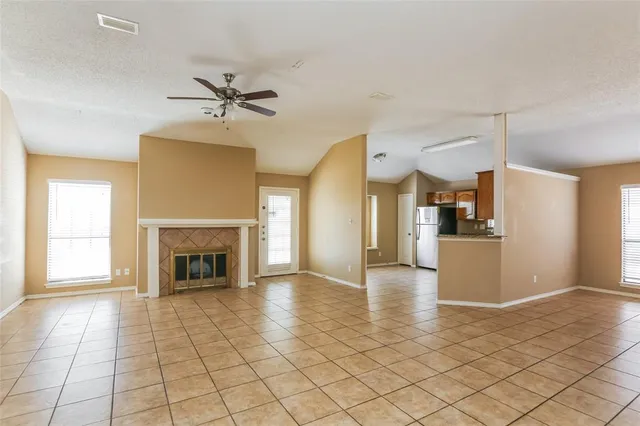 a view of a livingroom with a fireplace a ceiling fan and windows