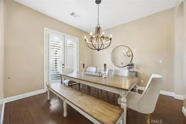 a dining room with wooden floor a chandelier a wooden table and chairs