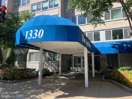 a front view of a building with garden and retail shops