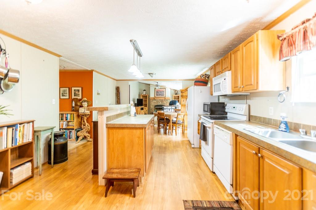 a kitchen with stainless steel appliances kitchen island granite countertop a refrigerator a stove top oven and a dining table with wooden floor