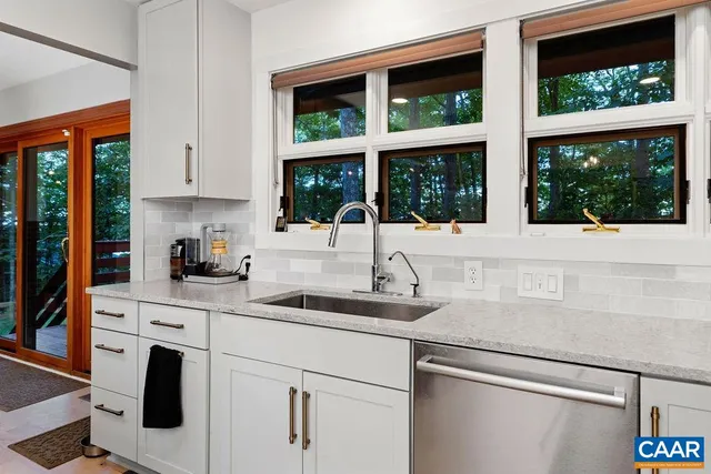 a kitchen with granite countertop a sink window and cabinets