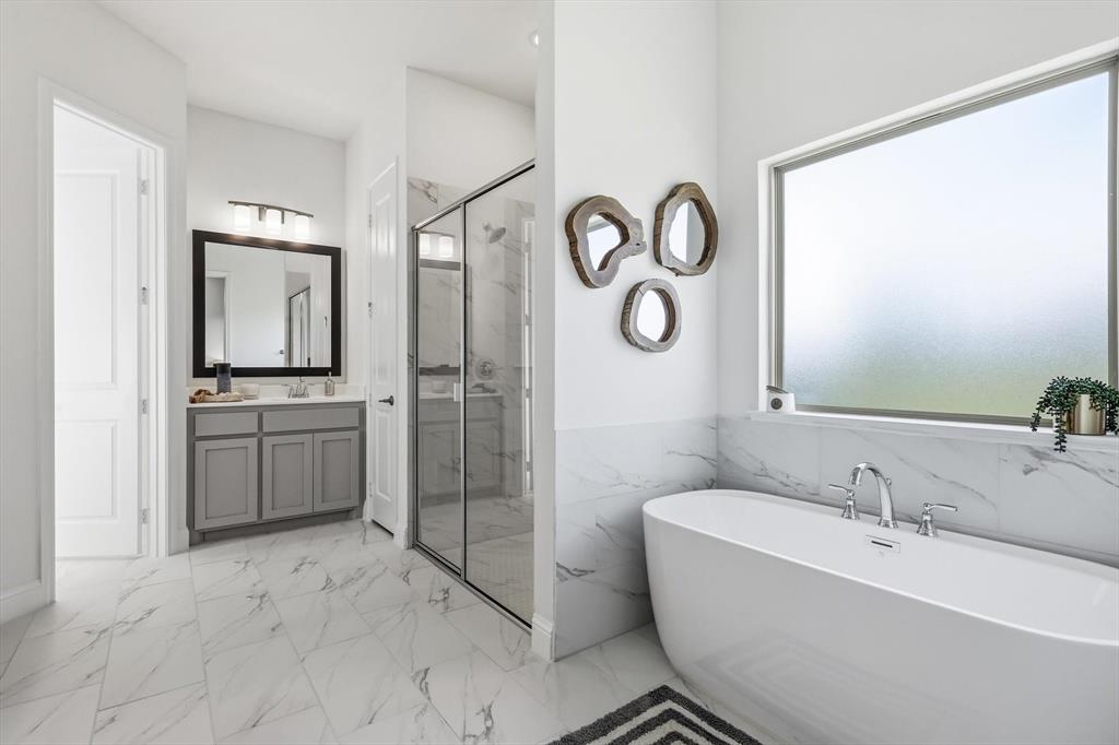 4017 Eagles Bluff Road Midlothian, TX 76065 - Photo 27 of 38 Spacious bathroom featuring a freestanding soaking tub with chrome fixtures, a large shower enclosure with glass doors, a single vanity with gray cabinetry, and white marble-look tile flooring