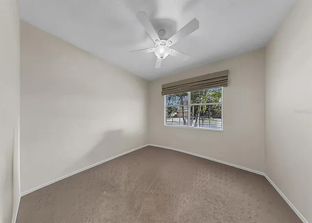 an empty room with a window and a fan