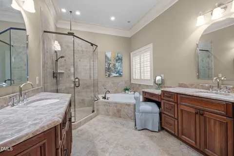 a spacious bathroom with a granite countertop double vanity sink a mirror and a shower