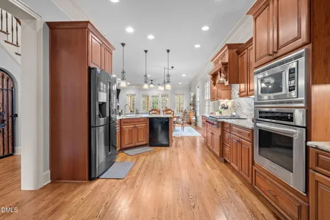 a kitchen with stainless steel appliances granite countertop a refrigerator a stove and a wooden floors