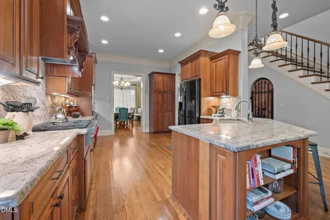 a kitchen with stainless steel appliances granite countertop a sink a stove and a wooden floors