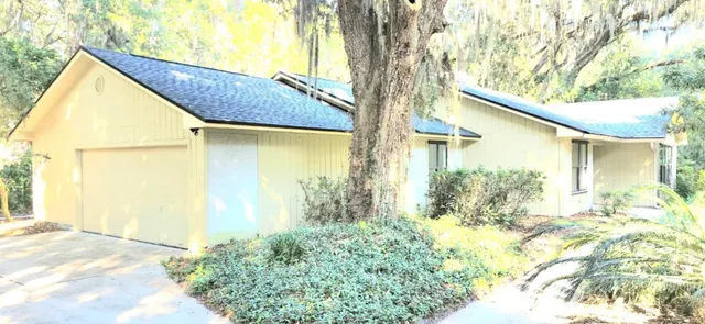 a view of yellow house with a large tree and wooden fence