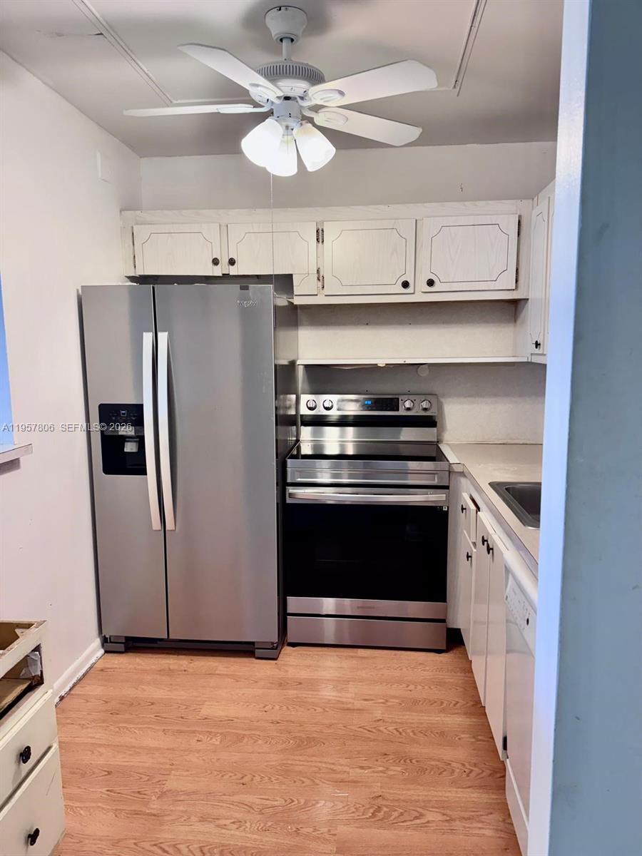 272 Dorset East, Unit G Boca Raton, FL 33434 - Photo 2 of 10 a kitchen with stainless steel appliances granite countertop a refrigerator a stove and a sink with wooden floor