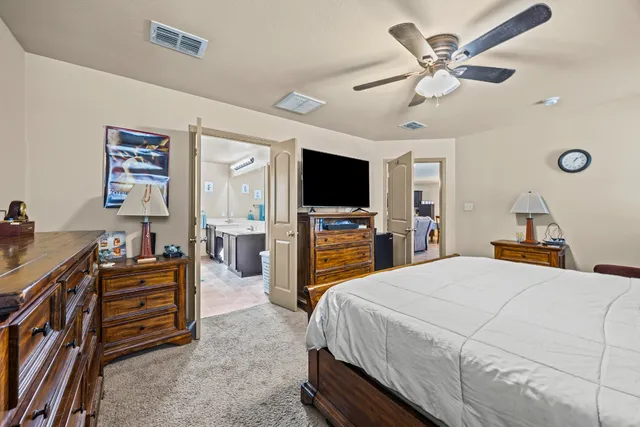 a bedroom with a bed and a flat tv screen on dresser