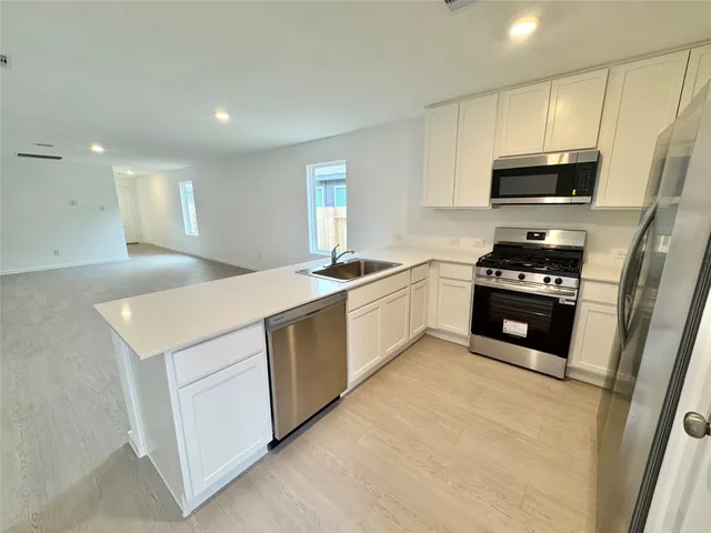 a kitchen with granite countertop a sink a stove and refrigerator