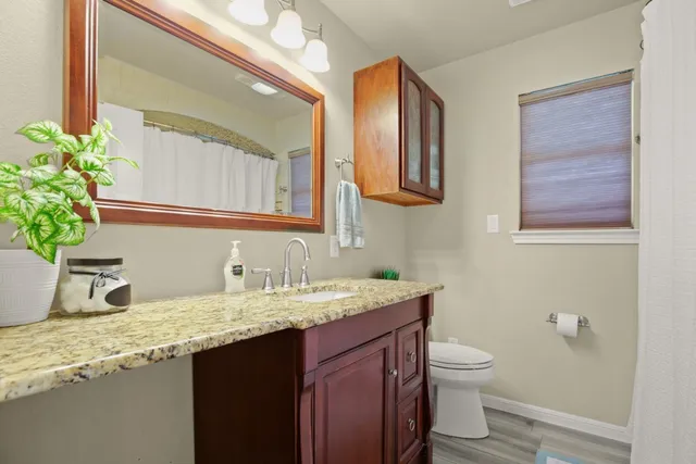 a bathroom with a granite countertop sink and a toilet