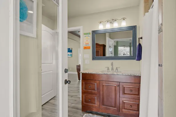a bathroom with a granite countertop sink a mirror and cabinets