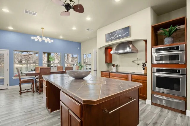 a kitchen with a stove a refrigerator and a dining table with wooden floor