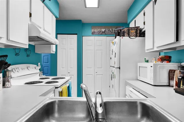 a kitchen with stainless steel appliances a refrigerator a sink a stove and white cabinets