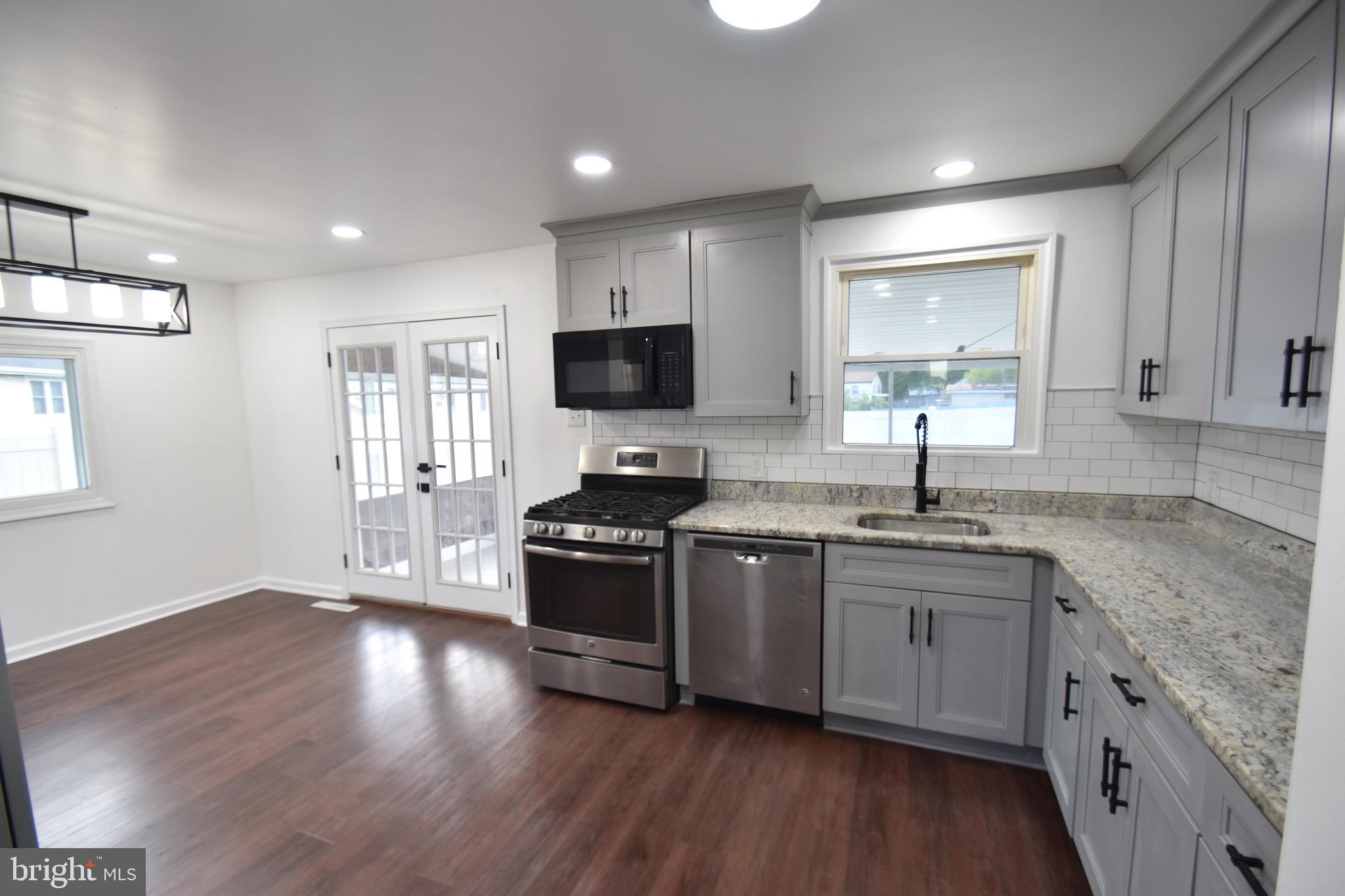 6 Russell Road New Castle, DE 19720 - Photo 6 of 16 a large kitchen with stainless steel appliances granite countertop a stove a sink a refrigerator and a granite counter tops with wooden floors