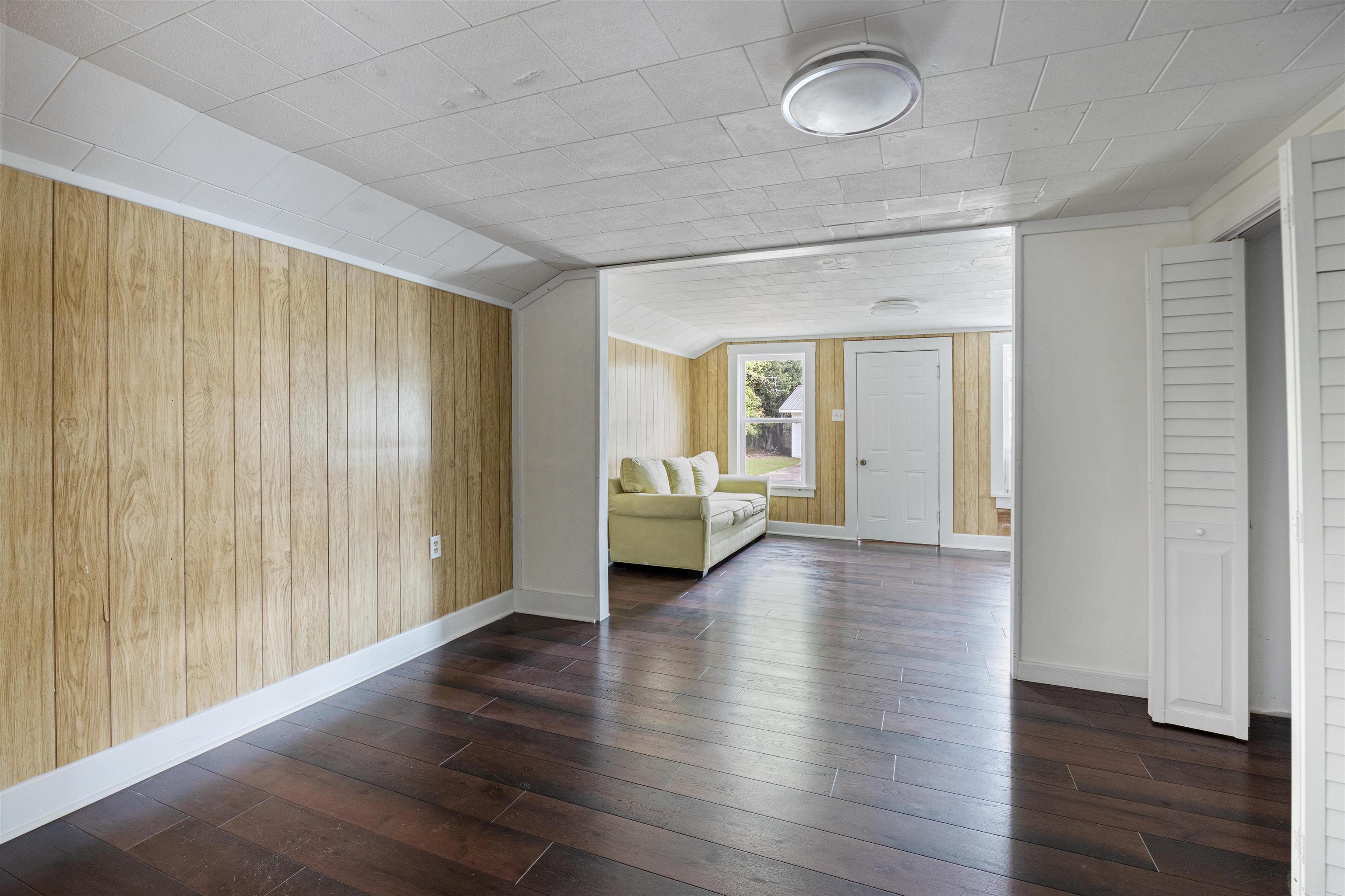 112 South Juniper Street Foley, AL 36535 - Photo 18 of 64 Unfurnished room featuring wood walls, dark wood-style floors, and lofted ceiling