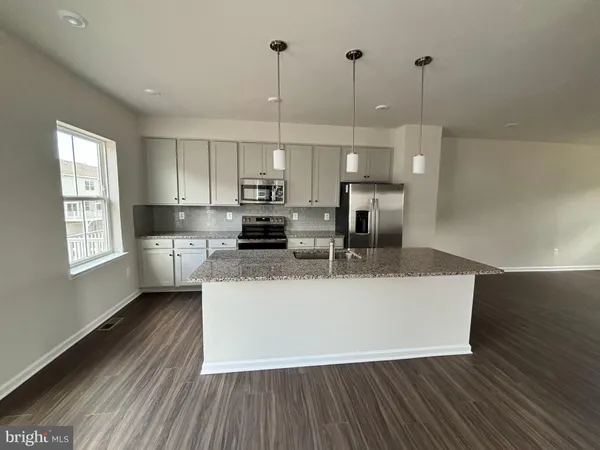 a view of kitchen with stainless steel appliances granite countertop a stove a sink a refrigerator white cabinets and wooden floor