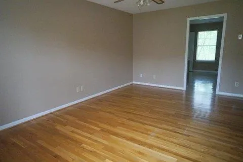 a view of an empty room with wooden floor and a window