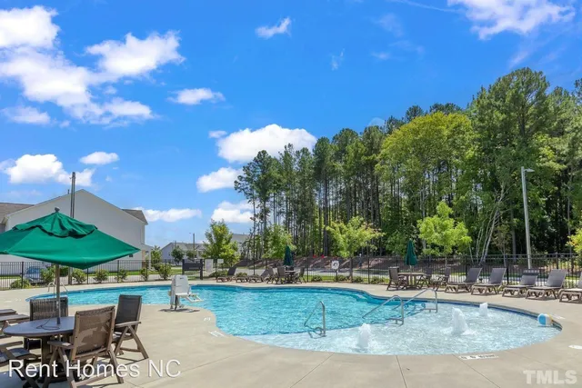a view of a swimming pool with a table and chairs under an umbrella