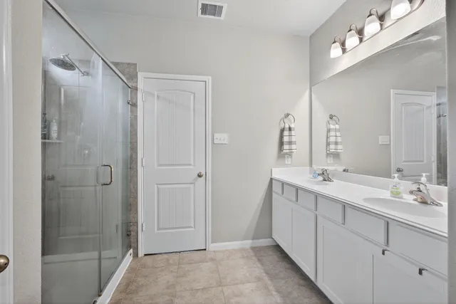 a bathroom with a double vanity sink mirror and shower
