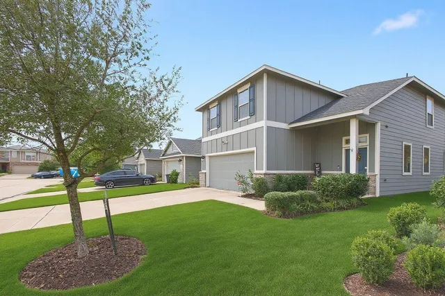 a view of a house with a yard and a large tree
