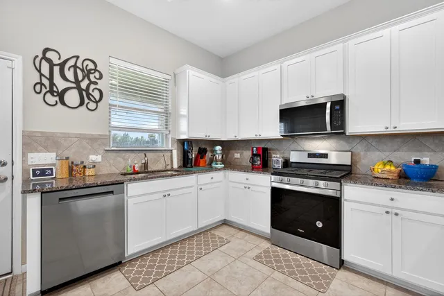 a kitchen with stainless steel appliances granite countertop a stove a sink and a microwave