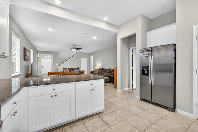 a kitchen with granite countertop a refrigerator and white cabinets