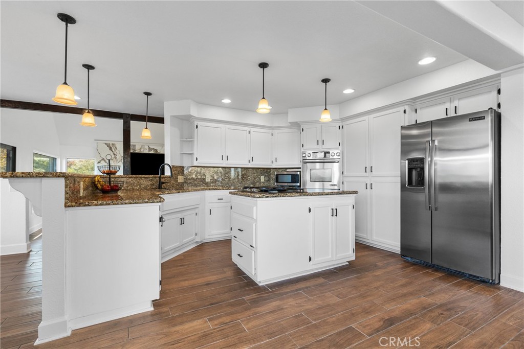 8110 Castenada Lane Atascadero, CA 93422 - Photo 18 of 75 a kitchen with stainless steel appliances kitchen island granite countertop a refrigerator a sink dishwasher a stove and white cabinets with wooden floor