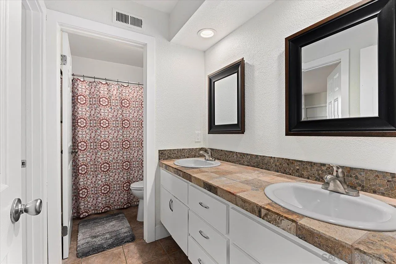 1321 Clear Crest Circle Vista, CA 92084 - Photo 20 of 30 a bathroom with a granite countertop sink a mirror a vanity and a shower