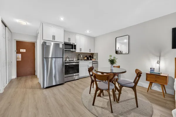 a kitchen with stainless steel appliances a refrigerator a stove a dining table and chairs