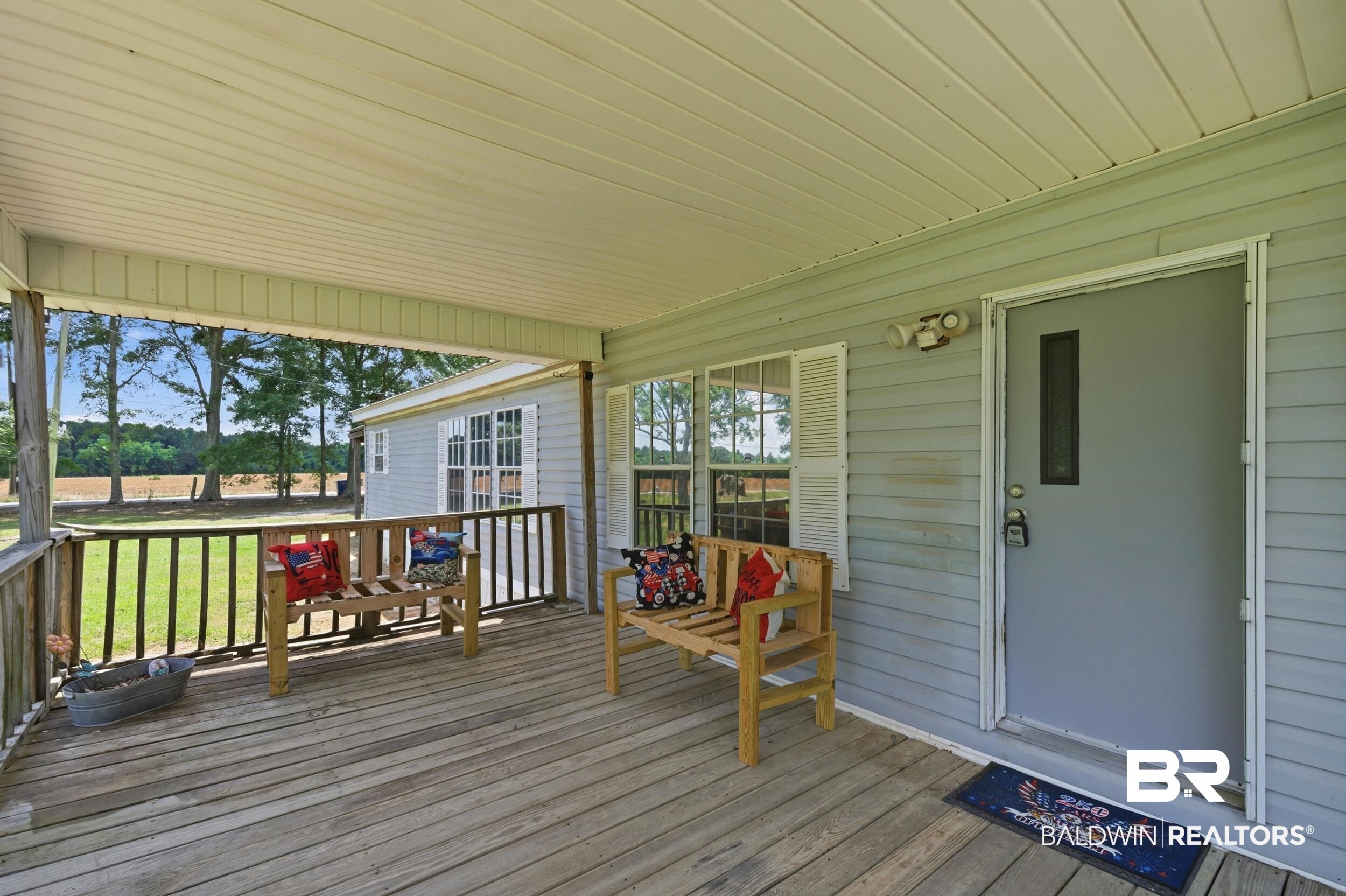 926 Tumbling Lane Atmore, AL 36502 - Photo 6 of 56 Expansive covered porch featuring wood-finish flooring, a white vinyl ceiling, and a wooden railing