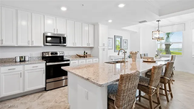 a kitchen with kitchen island granite countertop a table chairs sink and cabinets