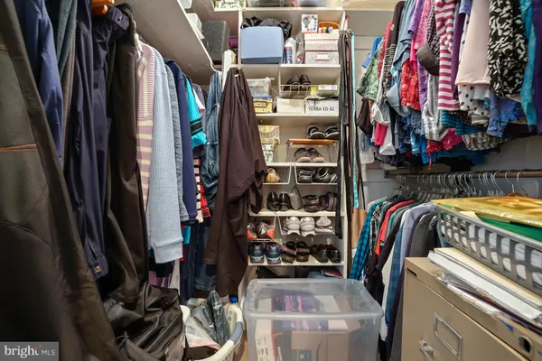 a view of walk in closet with clothes and shoes