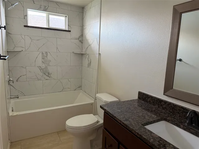 a bathroom with a granite countertop toilet a sink and bathtub