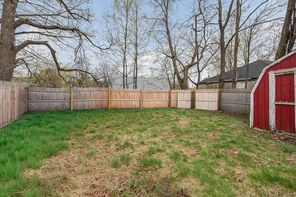 a view of backyard with tree and wooden fence
