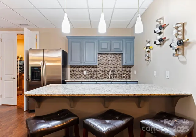 a kitchen with stainless steel appliances granite countertop a table chairs in it and wooden floors