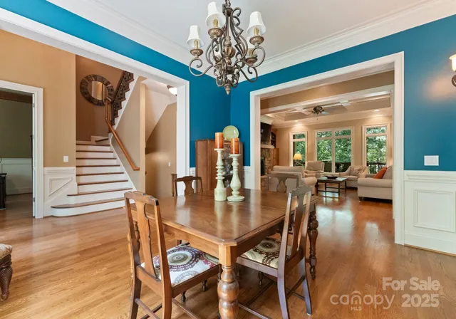 a dining room with wooden floor a chandelier a wooden table and chairs
