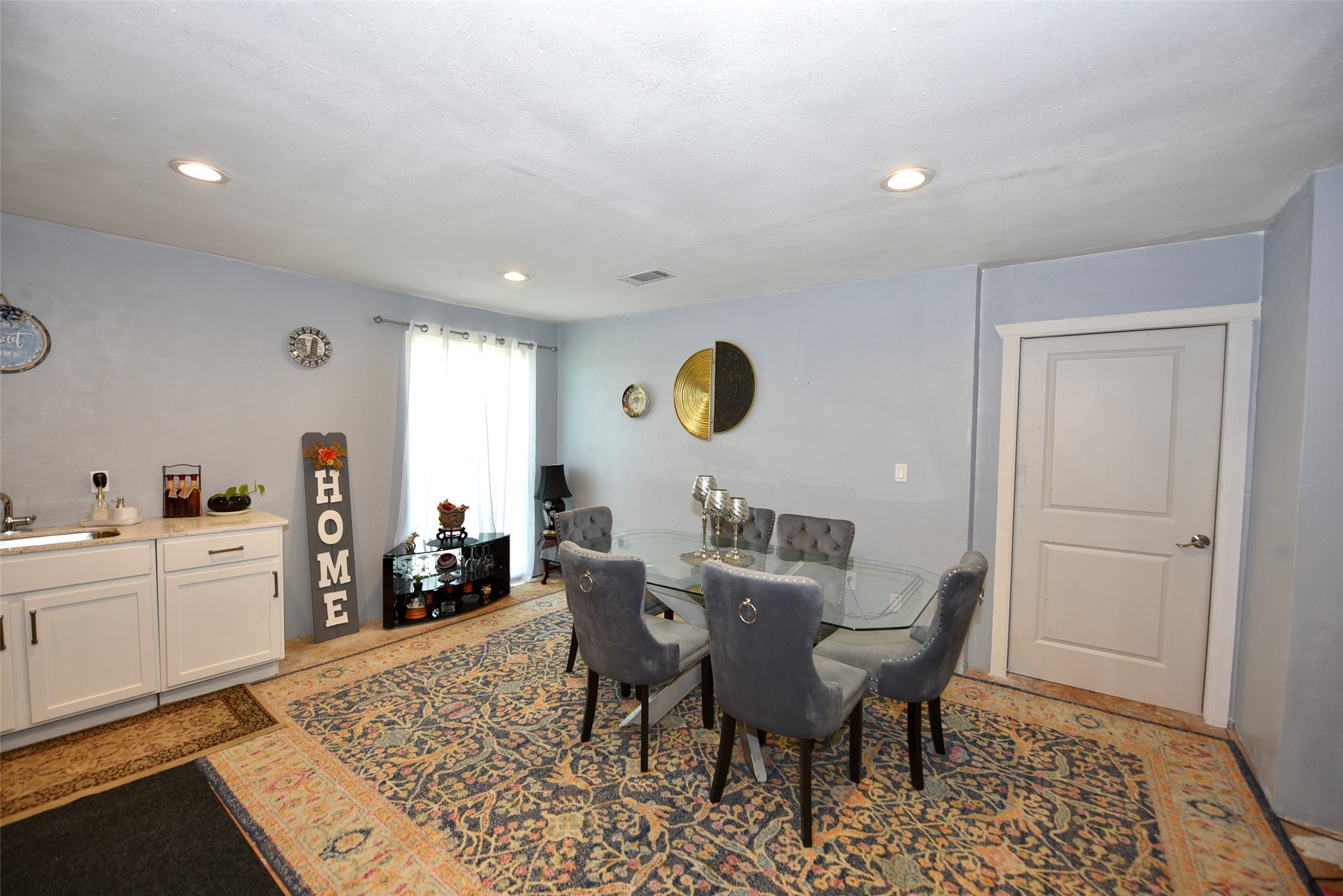 382 Road 5251 Cleveland, TX 77327 - Photo 12 of 22 This cozy dining area features a glass-top table with elegant chairs, soft blue walls, and recessed lighting. The space includes a small white kitchenette and decorative accents, creating a welcoming atmosphere.